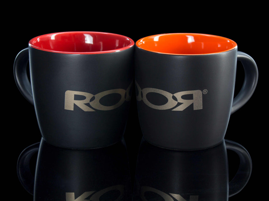 Two ROOR Collectors Mugs with matte black exterior and red and orange interiors, featuring assorted decals.