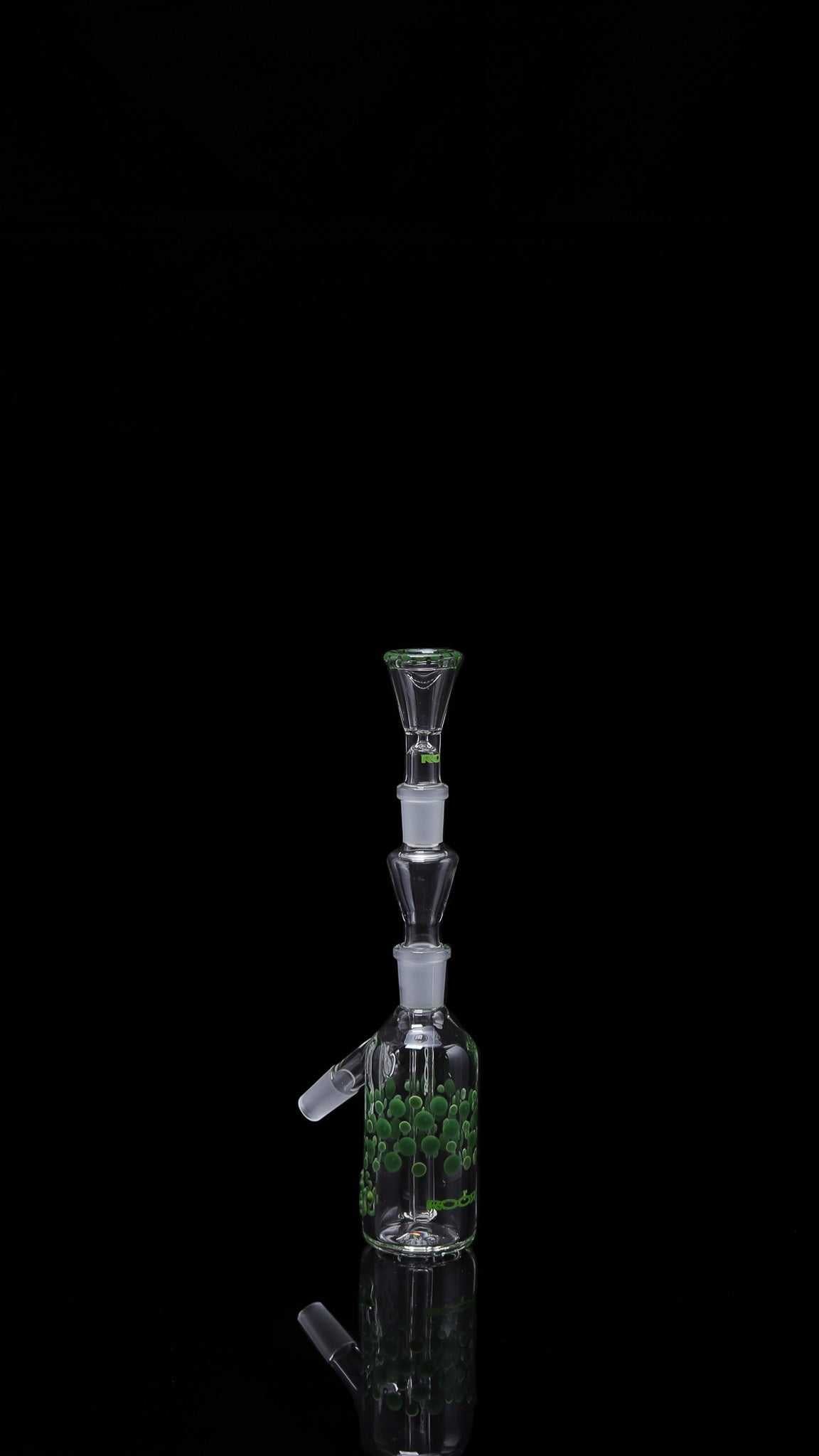 ROOR® Classic Ash Catcher 14.5mm joint with green pearl dot design on clear glass body isolated on black background