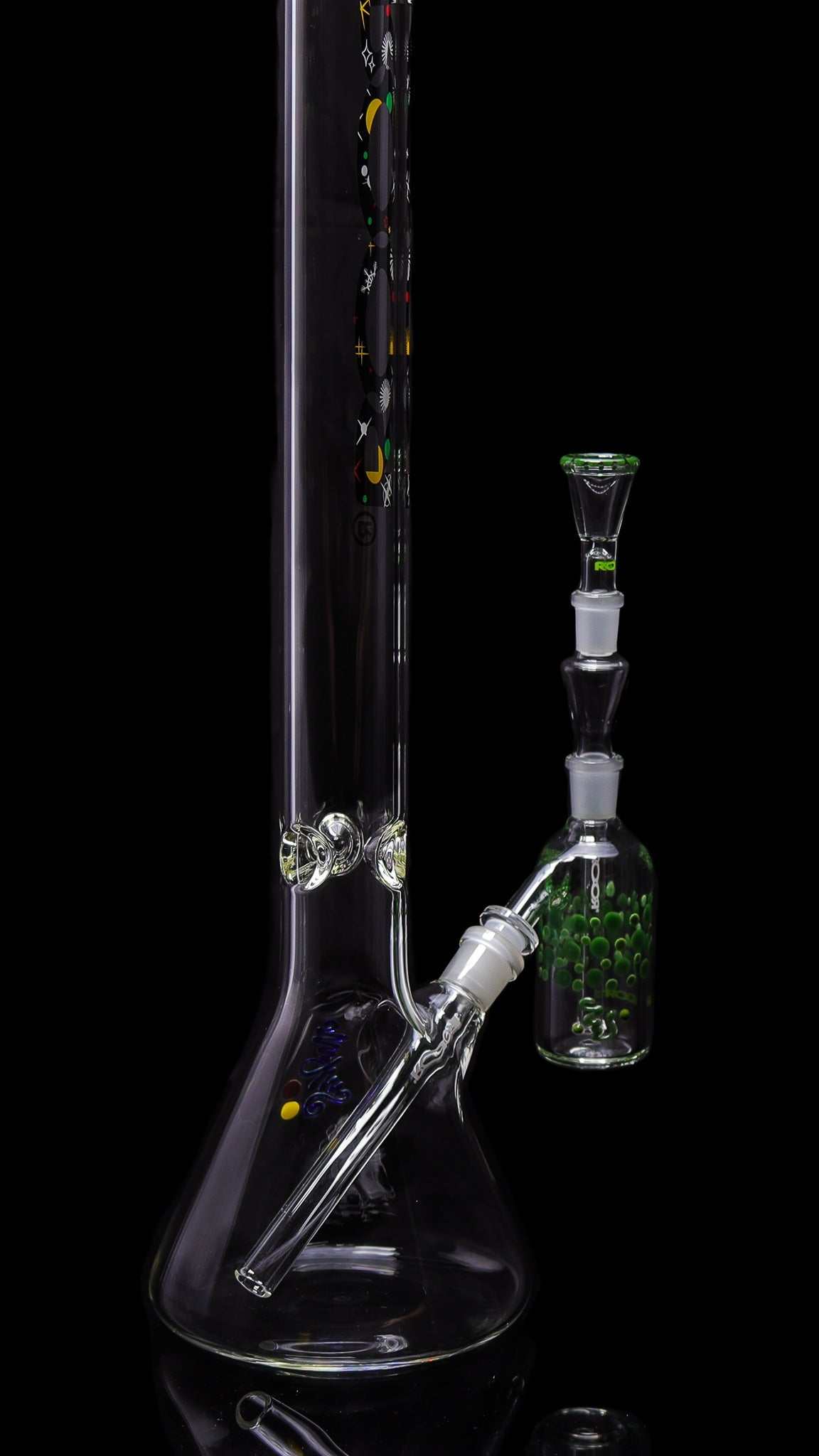 ROOR® Classic Ash Catcher 14.5mm joint with green pearl dot design attached to a clear glass beaker bong.