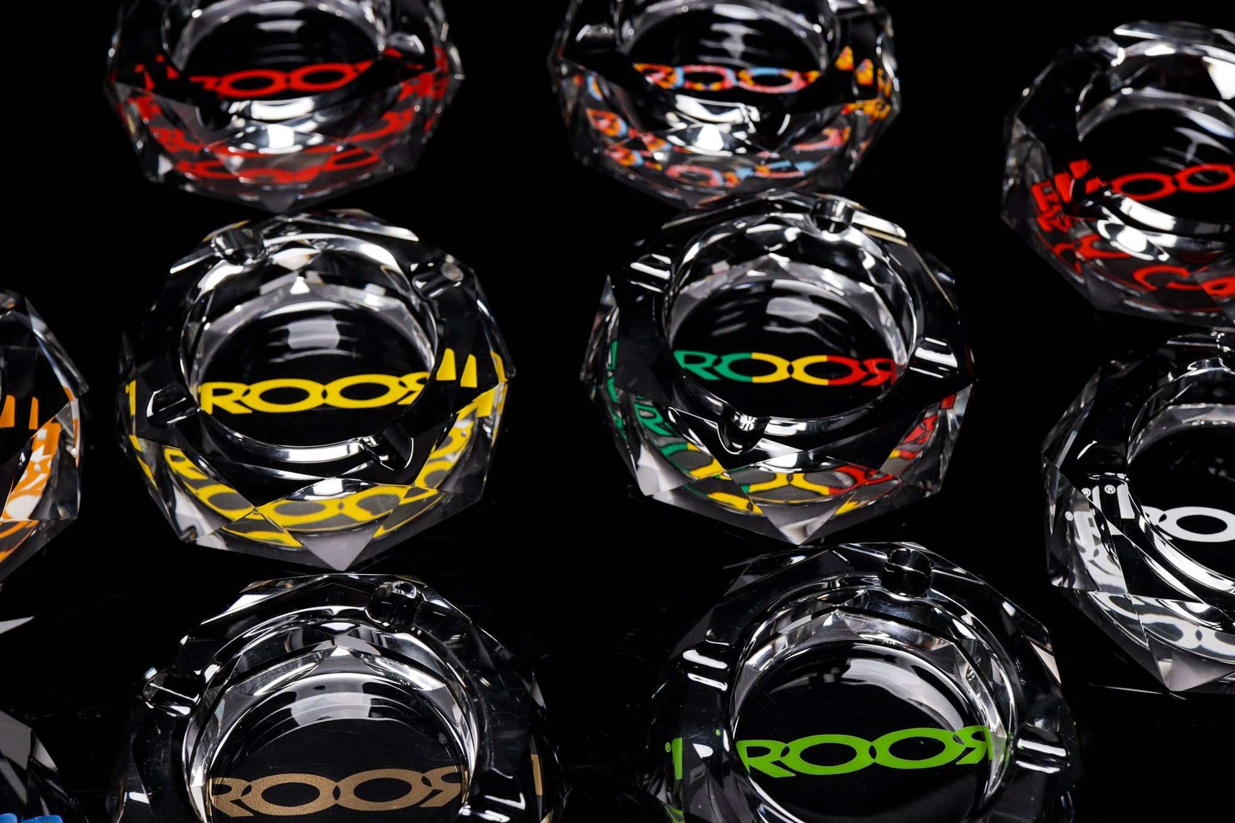 ROOR glass crystal cut ashtrays with colorful decal designs on a black background