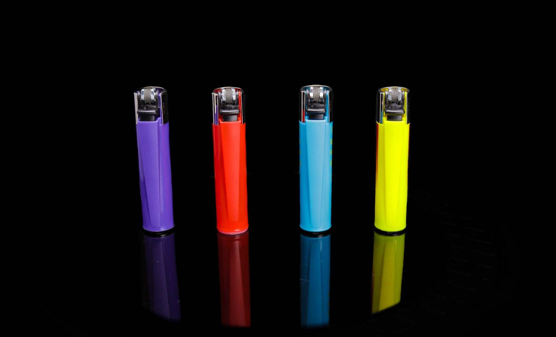 Four colorful Clipper lighters in purple, red, blue, and yellow with a hippie peace and freedom design on black background.