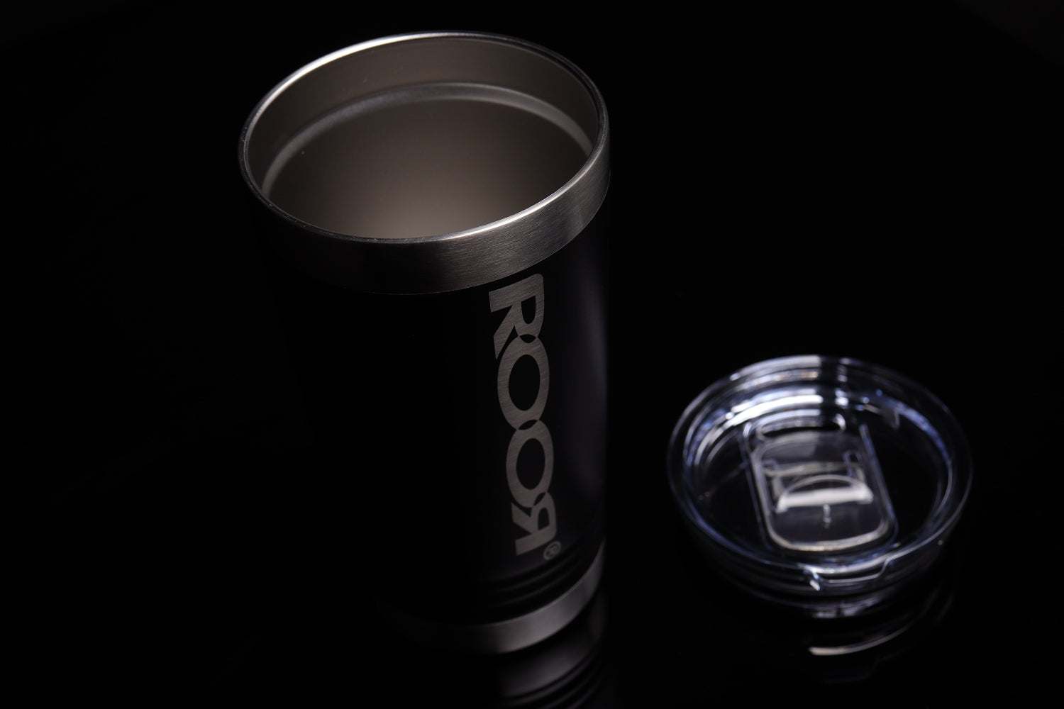 Black ROOR Tumbler 16oz stainless steel with laser-engraved logo and clear slider lid beside it on black background
