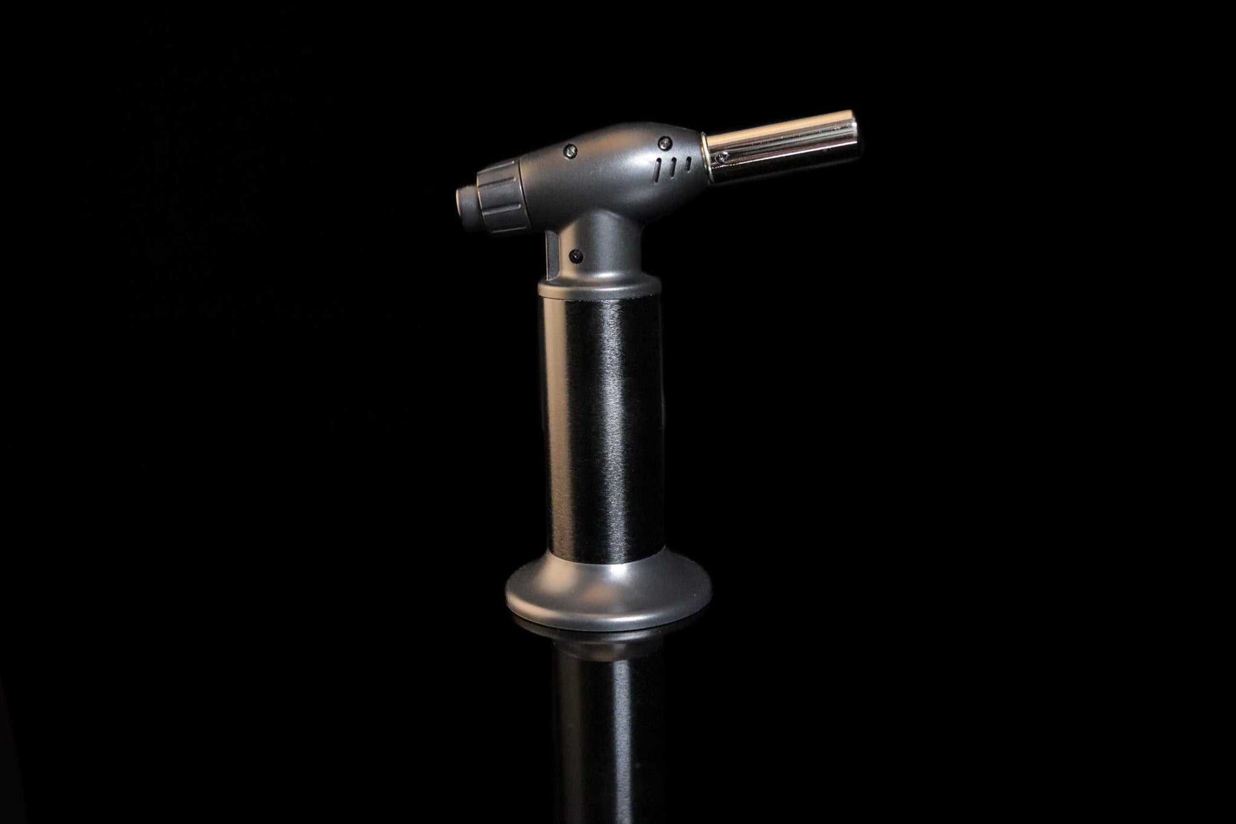 Newport Zero Jumbo Butane Torch with ergonomic black handle and silver nozzle on black background