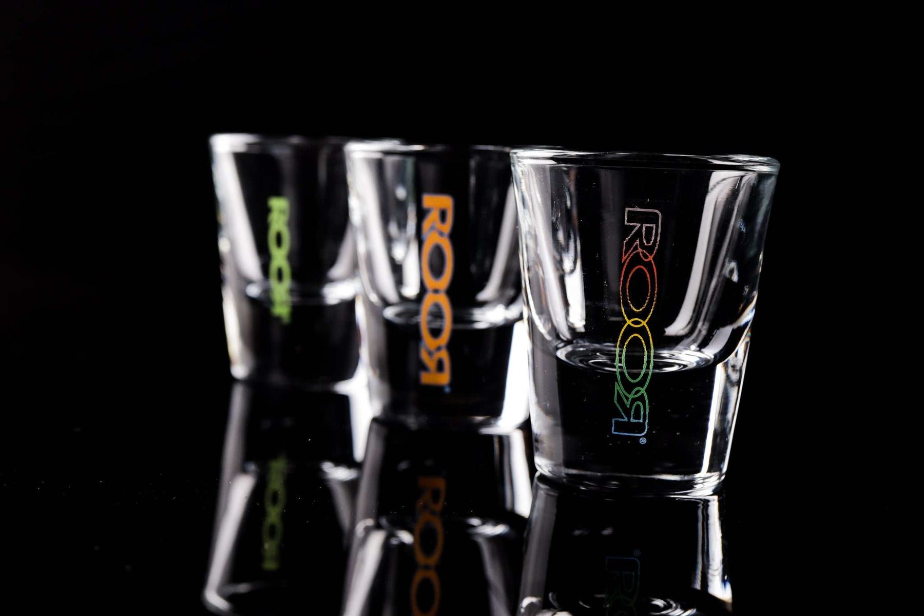 ROOR Shot Glass with thick clear base and assorted decals on black background.