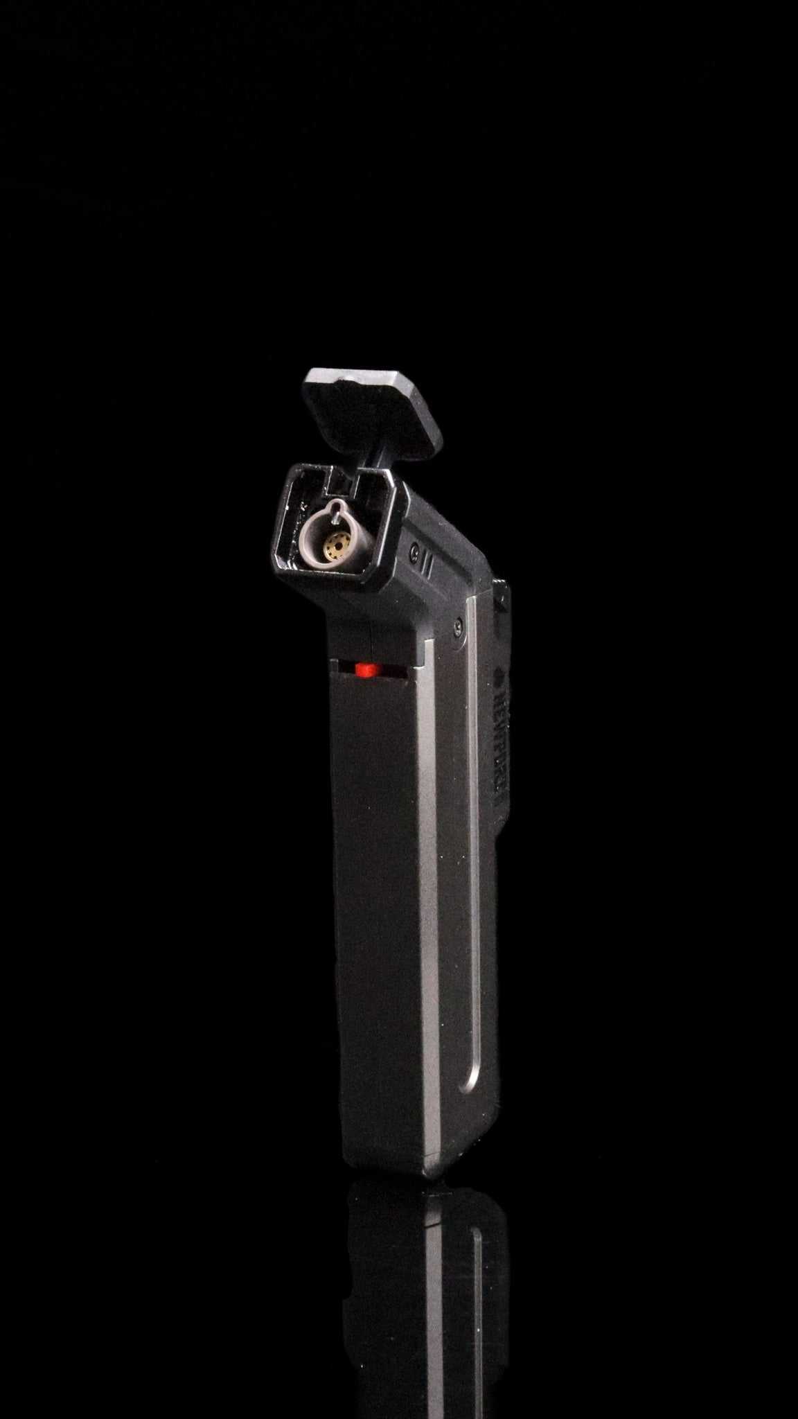 Newport Zero metallic lighter standing upright on a reflective surface.