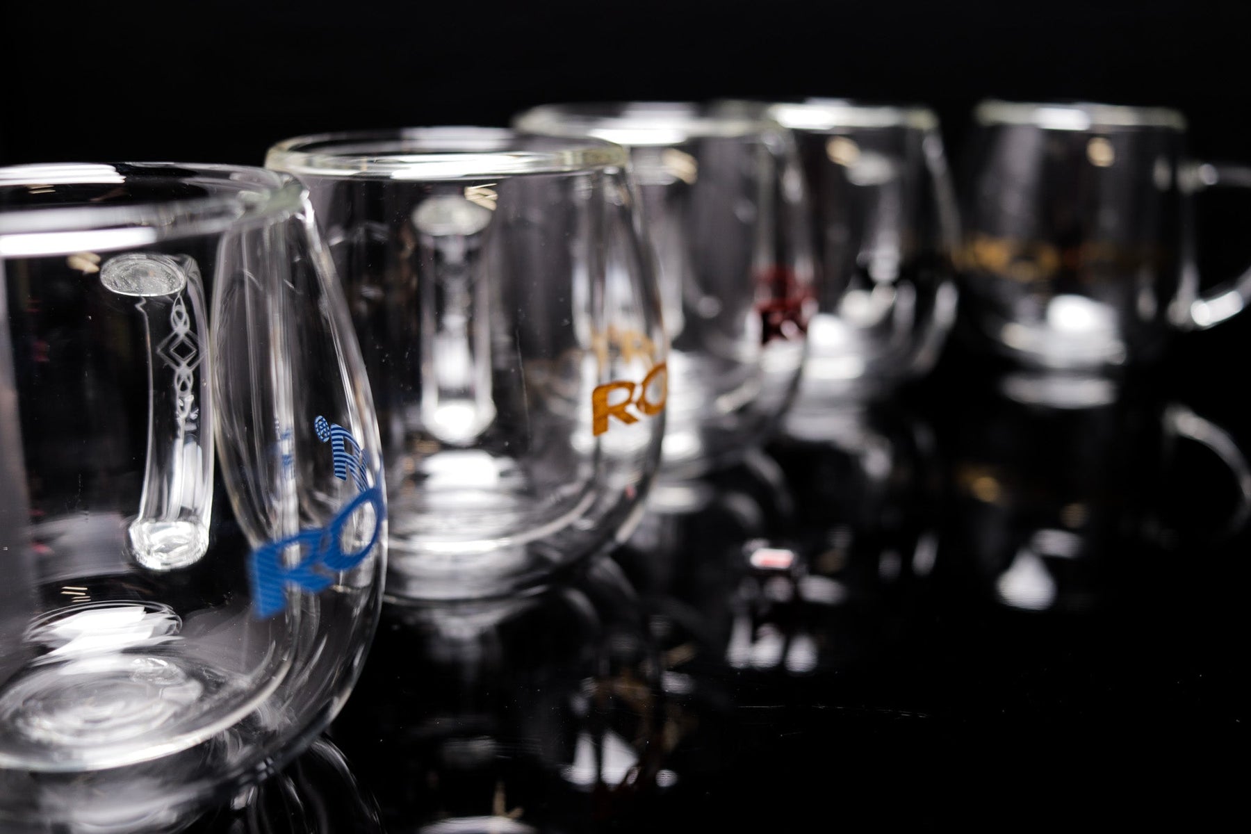 ROOR® Glass Mugs Double Layer with decals on a reflective surface.